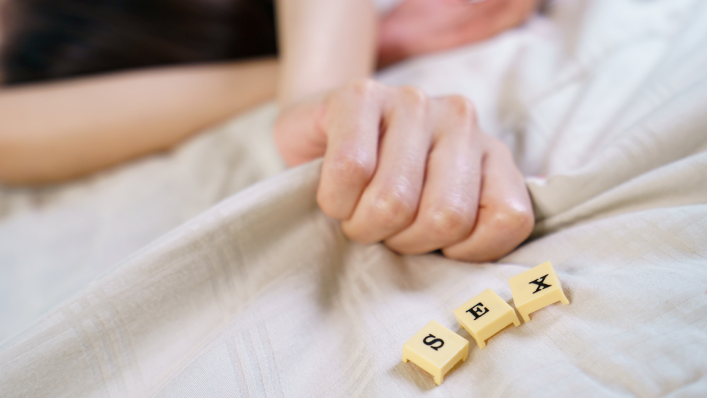 Image of two hands holding on a bet with scrabble letters spelling sex